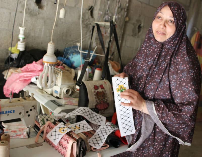 Woman in traditional dress showcasing handmade embroidery in a workshop setting.