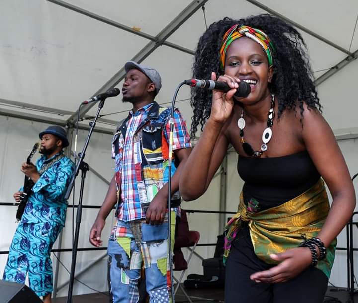 Live band performing energetically on stage with vibrant outfits and joyful expressions.