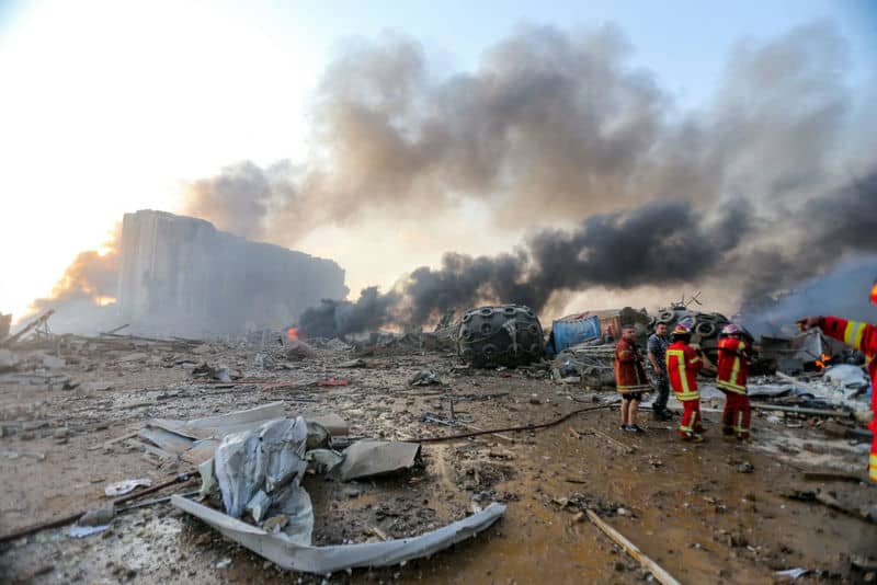 Firefighters at an urban disaster scene amidst smoke and debris, responding to a building explosion aftermath.