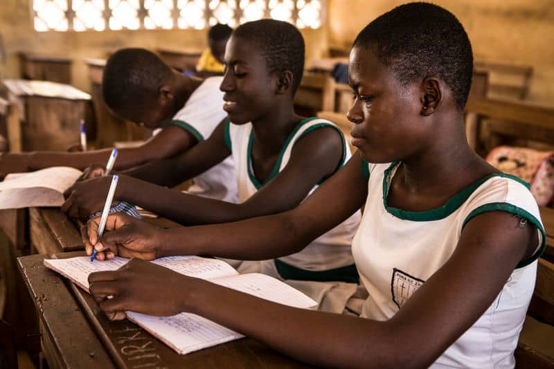 Students in classroom focused on writing notes during a lesson.