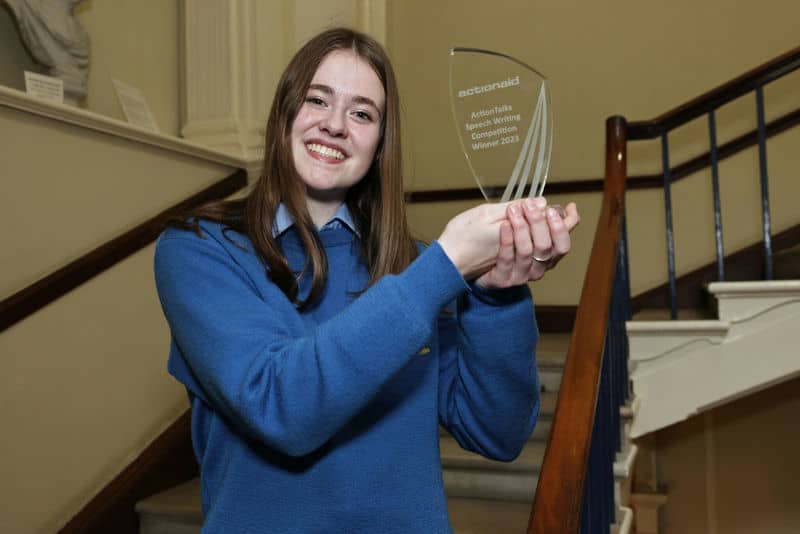 Person holding a trophy on a staircase, smiling, celebrating award achievement.