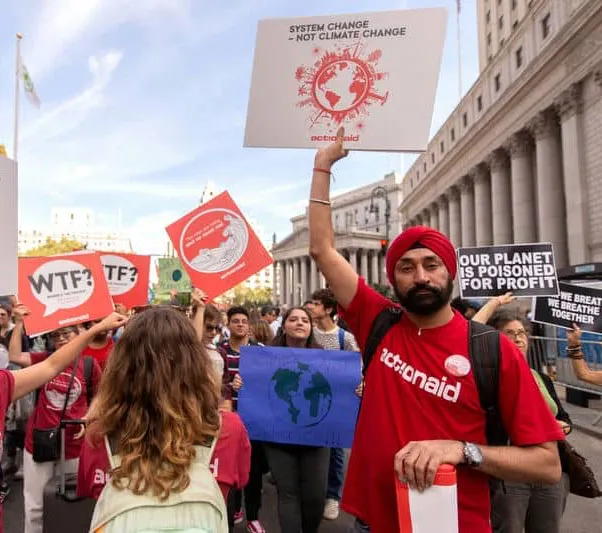People protest climate change holding signs, including System change, not climate change, at a city march.