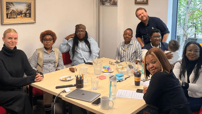 A diverse team of colleagues in a meeting around a table, discussing ideas and collaborating in an office setting.