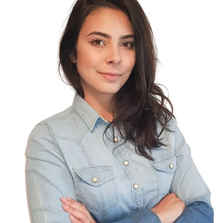 Young woman in denim shirt with crossed arms, smiling confidently at the camera.