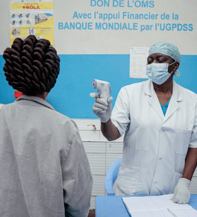Healthcare worker checks temperature with infrared thermometer during a medical screening in a clinical setting.